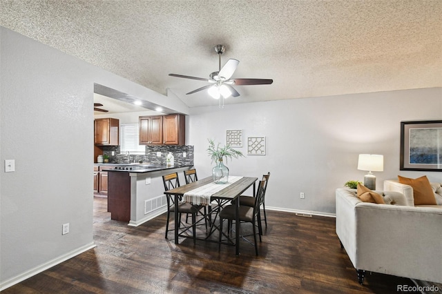 dining space featuring dark wood-type flooring, ceiling fan, and a textured ceiling