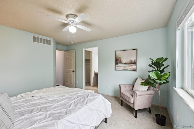 bedroom featuring ceiling fan, a spacious closet, light carpet, and a textured ceiling