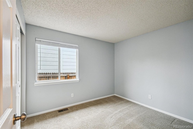 carpeted empty room featuring a textured ceiling