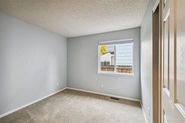 carpeted empty room featuring a textured ceiling