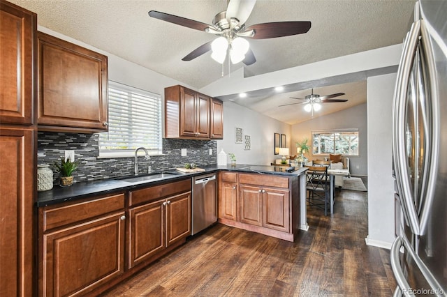 kitchen featuring vaulted ceiling, appliances with stainless steel finishes, sink, backsplash, and kitchen peninsula