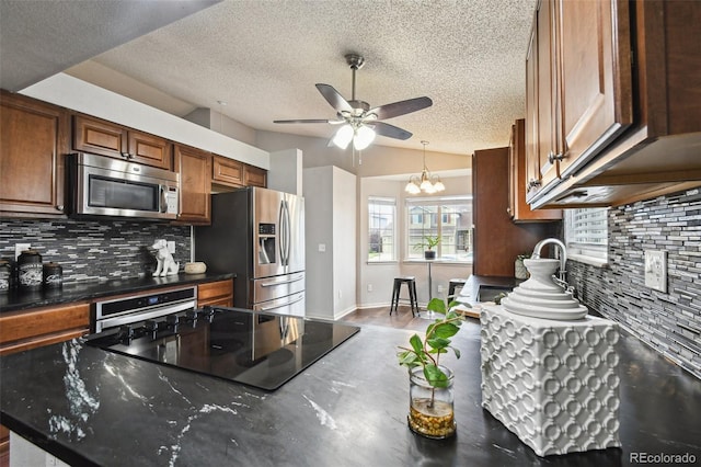 kitchen with lofted ceiling, tasteful backsplash, a textured ceiling, appliances with stainless steel finishes, and ceiling fan with notable chandelier