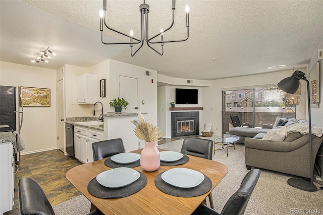 dining room with a tile fireplace, sink, a chandelier, and a textured ceiling