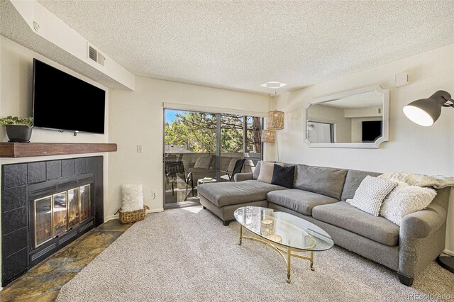 carpeted living room featuring a fireplace and a textured ceiling