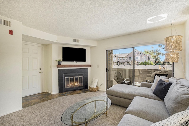 carpeted living room featuring a textured ceiling and a tiled fireplace