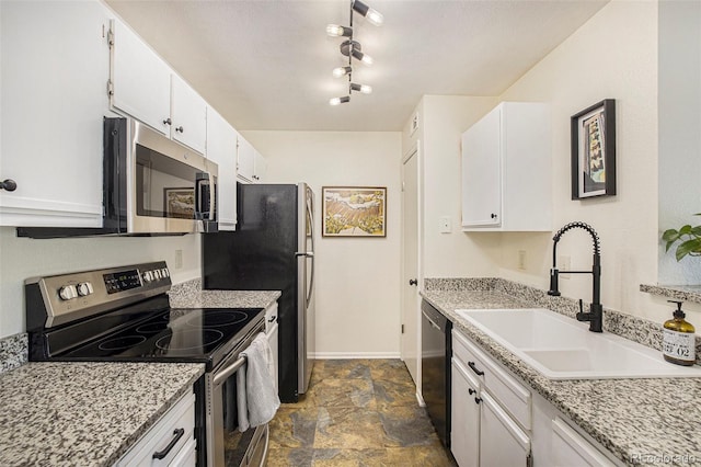 kitchen with light stone countertops, stainless steel appliances, white cabinetry, and sink