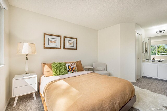 carpeted bedroom featuring a textured ceiling, connected bathroom, and a closet