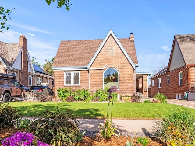 1528 Holly St, Denver, CO 80220 - tudor house with brick siding, a front lawn, a chimney, and a shingled roof