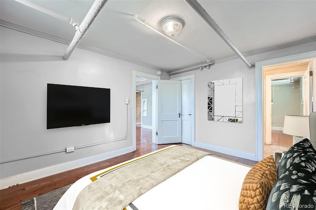 bedroom with wood finished floors, baseboards, and crown molding