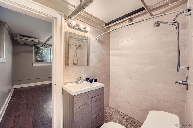 bathroom featuring toilet, a tile shower, vanity, and wood finished floors