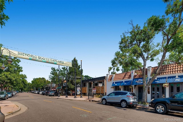 view of asphalt street featuring curbs, sidewalks, and street lighting