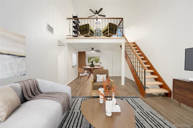 living room with ceiling fan, hardwood / wood-style flooring, and a high ceiling