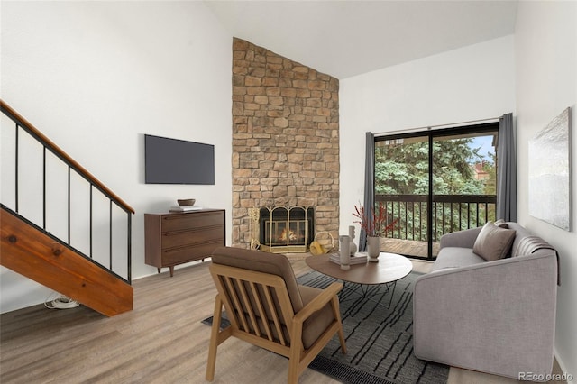 living room featuring high vaulted ceiling, light wood-type flooring, and a fireplace