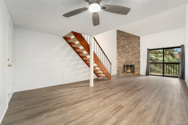 unfurnished living room featuring ceiling fan, a textured ceiling, wood-type flooring, vaulted ceiling, and a fireplace