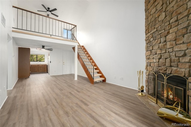 unfurnished living room with hardwood / wood-style floors, a high ceiling, sink, and a fireplace