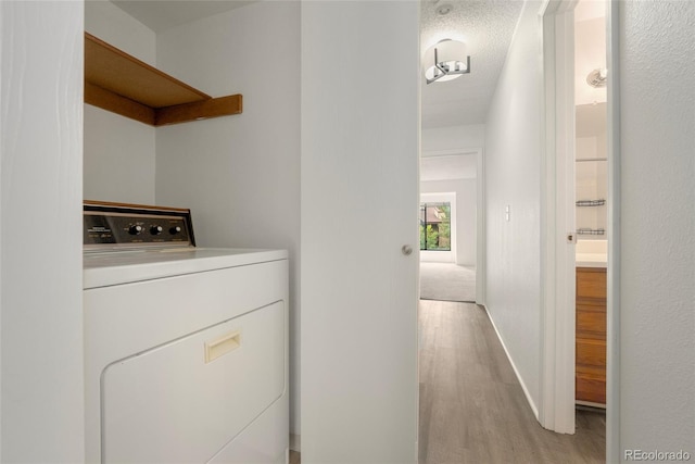 laundry room featuring a textured ceiling, washer / clothes dryer, and light hardwood / wood-style flooring