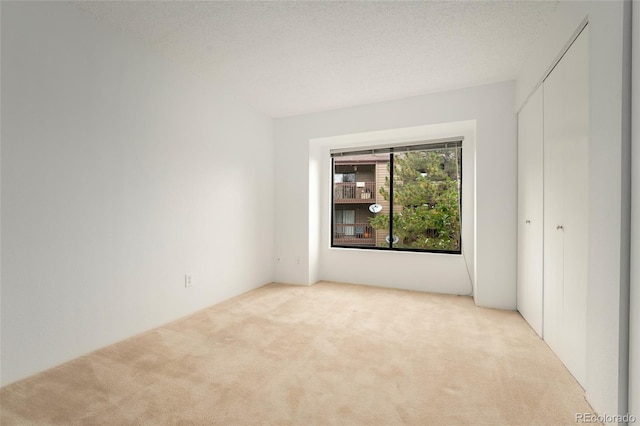 unfurnished room featuring light carpet and a textured ceiling