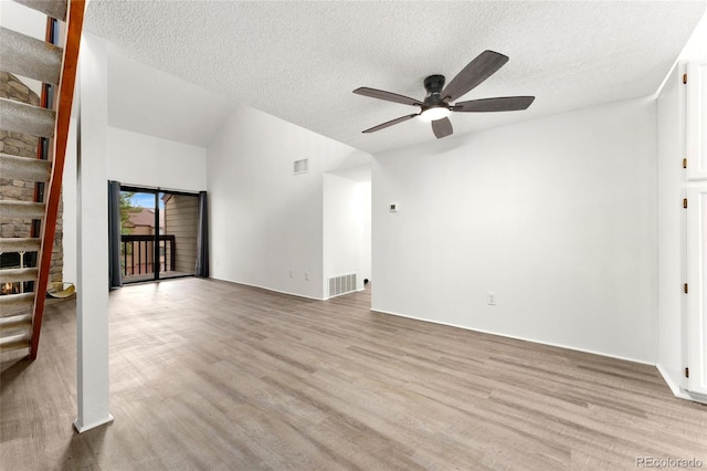 unfurnished living room with visible vents, a stone fireplace, and wood finished floors