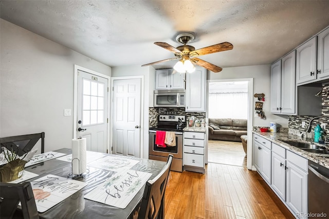 327 N 12th Ave, Brighton, CO 80601 - kitchen with stainless steel appliances, decorative backsplash, a ceiling fan, light wood-type flooring, and light stone countertops