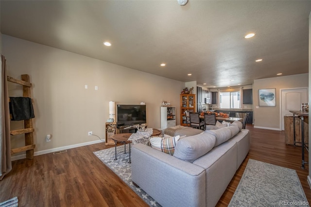 living room with dark wood-style floors, baseboards, visible vents, and recessed lighting