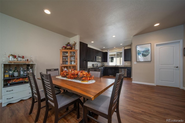 dining area featuring a textured ceiling, baseboards, dark wood-type flooring, and recessed lighting