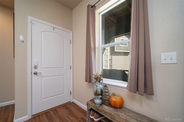 doorway with dark wood-style flooring and baseboards