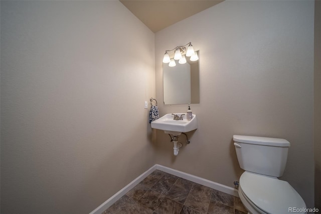 half bathroom featuring a sink, toilet, and baseboards