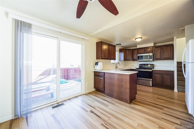 kitchen with kitchen peninsula, sink, light hardwood / wood-style floors, and appliances with stainless steel finishes