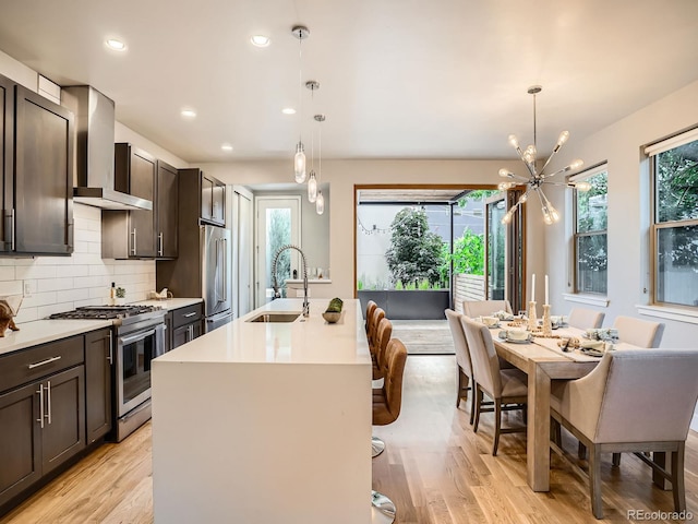 4535 Stuart St, Denver, CO 80212 - kitchen featuring appliances with stainless steel finishes, wall chimney range hood, a chandelier, light wood finished floors, and recessed lighting