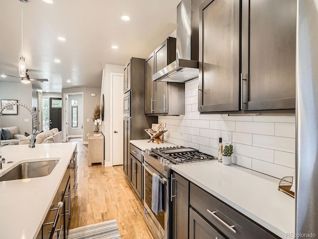 4535 Stuart St, Denver, CO 80212 - kitchen featuring wall chimney range hood, appliances with stainless steel finishes, open floor plan, light wood finished floors, and ceiling fan
