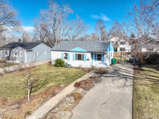 view of front of property with fence, a front yard, and a shingled roof