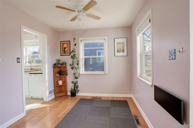 interior space featuring light wood-type flooring, baseboards, a healthy amount of sunlight, and visible vents