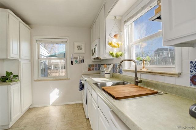 kitchen featuring white cabinets, white appliances, light countertops, and a sink