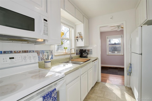 kitchen featuring tasteful backsplash, light countertops, white appliances, white cabinetry, and a sink