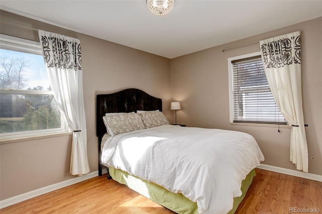 bedroom featuring multiple windows, baseboards, and wood finished floors