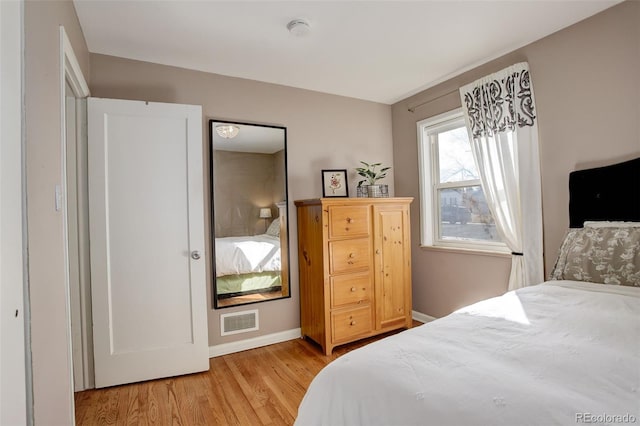 bedroom with visible vents, baseboards, and light wood finished floors