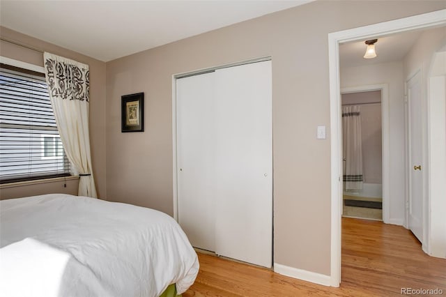 bedroom with a closet, light wood-type flooring, and baseboards