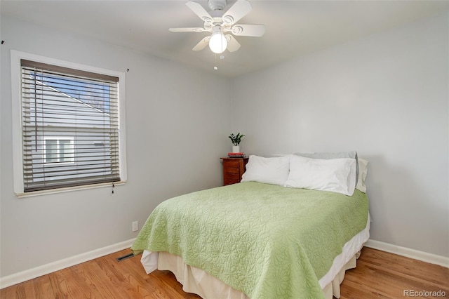 bedroom featuring visible vents, a ceiling fan, baseboards, and wood finished floors