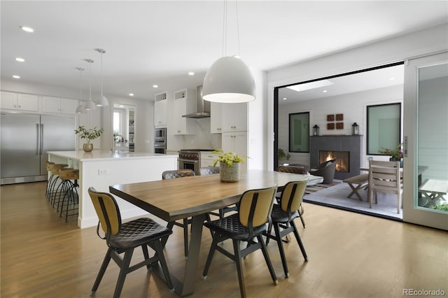 3450 S Cherry St, Denver, CO 80222 - dining room featuring a lit fireplace, recessed lighting, and light wood-style flooring