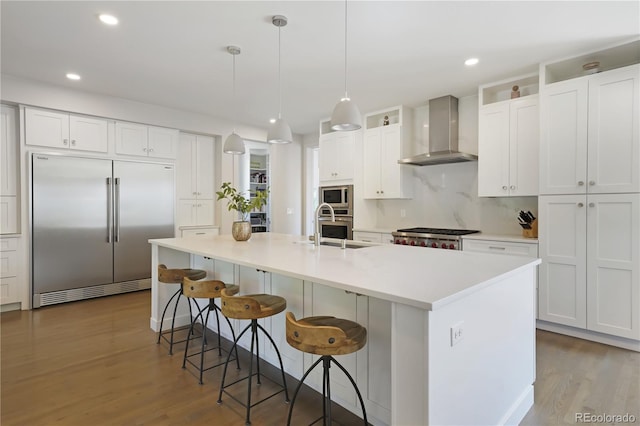 3450 S Cherry St, Denver, CO 80222 - kitchen featuring built in appliances, wall chimney range hood, wood finished floors, a breakfast bar area, and recessed lighting