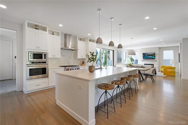 3450 S Cherry St, Denver, CO 80222 - kitchen featuring stainless steel appliances, wall chimney range hood, white cabinets, a spacious island, and recessed lighting