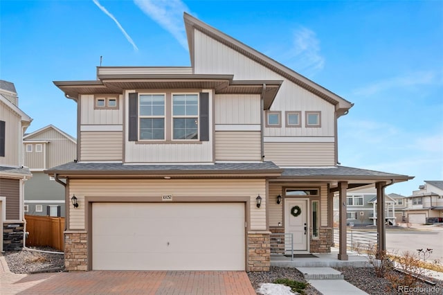 townhome / multi-family property featuring an attached garage, fence, stone siding, decorative driveway, and roof with shingles