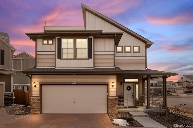 townhome / multi-family property featuring a garage, stone siding, fence, and decorative driveway