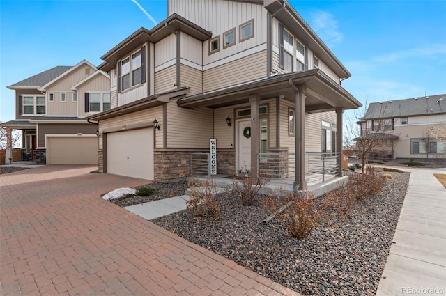 view of front of property featuring decorative driveway, a porch, an attached garage, board and batten siding, and stone siding