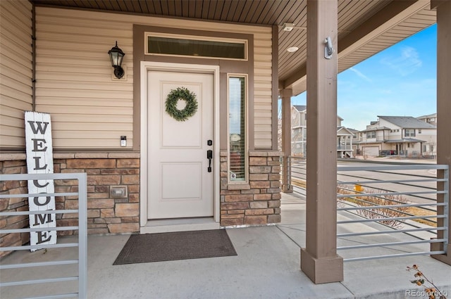 doorway to property featuring a porch, a residential view, and stone siding