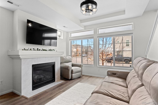 living area with baseboards, visible vents, wood finished floors, and a tile fireplace