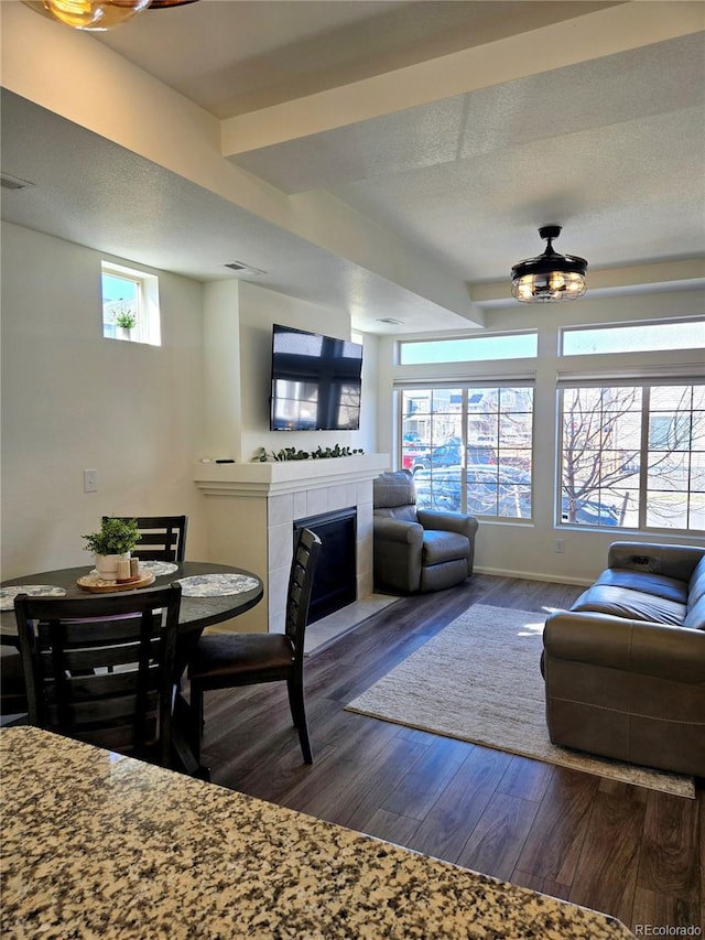 dining room featuring a textured ceiling, a fireplace, wood finished floors, visible vents, and baseboards