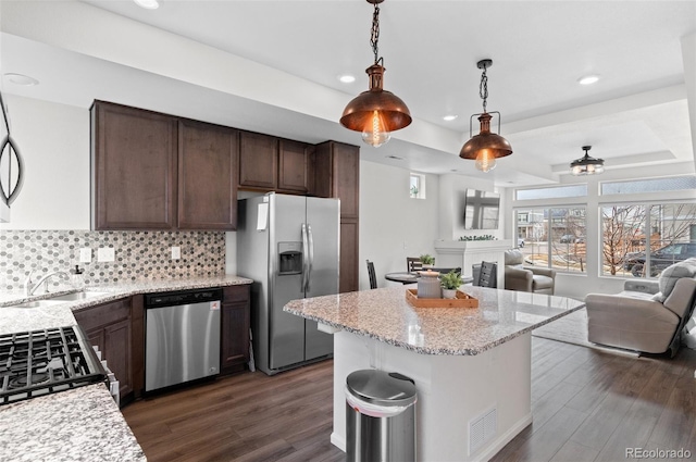 kitchen with a sink, stainless steel appliances, open floor plan, and a raised ceiling