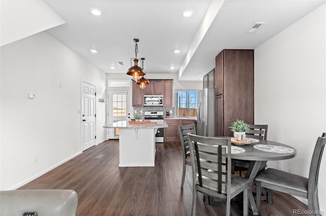 kitchen with a center island, dark wood finished floors, tasteful backsplash, appliances with stainless steel finishes, and baseboards