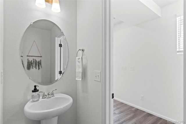 bathroom with wood finished floors, a sink, and baseboards